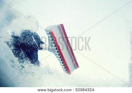 winter driving - scraping ice from a windshield