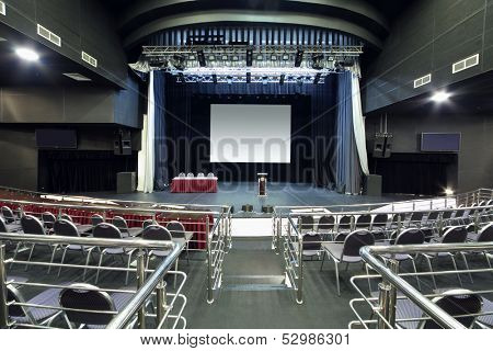 Chairs with handrails and stage with desk in modern hall for business meetings.  