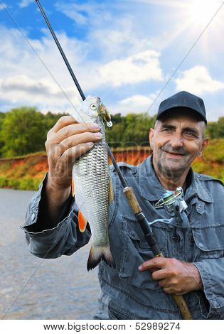 Chub In The Hand Of Fisherman Against The Sky And The River