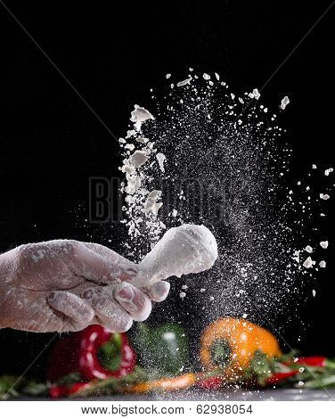 Chicken meat with flour in freeze motion, isolated on black background