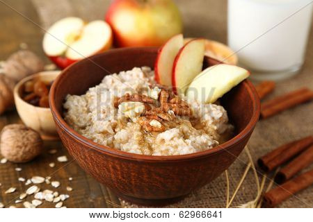 Tasty oatmeal with nuts and apples on wooden table