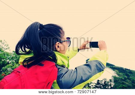 woman hiker taking photo with cell phone at peak of emei mountain, china