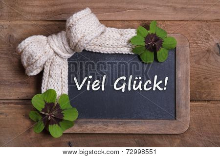 Menu board with good luck message in german - clovers and white bow on wooden background