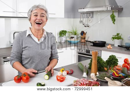 Senior or older woman with grey hair cooking in kitchen - vegetables