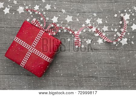 Christmas Present wrapped in red paper on a wooden background for a voucher coupon - greeting card country style