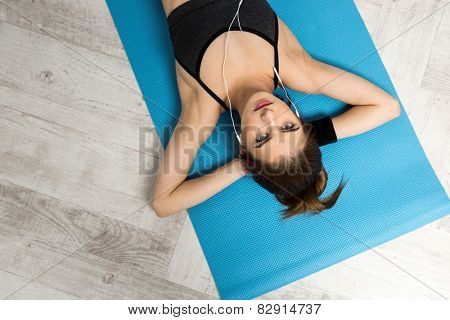 Top view portrait of a young woman resting on the yoga mat at gym