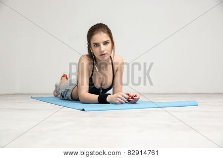 Portrait of a beautiful sports woman lying on the yoga mat 