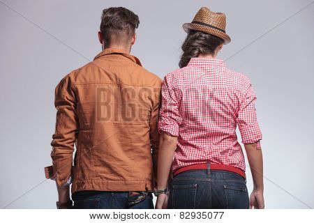 Rear view of a young couple posing on grey studion background.