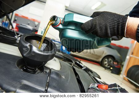 auto mechanic technician replacing and pouring motor oil into automobile engine at maintenance repair service station