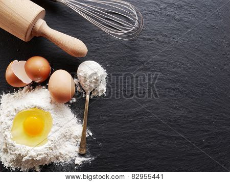 Dough preparation. Baking ingredients: egg and flour on black board.