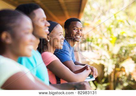 cheerful young african college boy with friends on campus