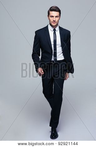 Full length portrait of a fashion male model over gray background. Looking at camera