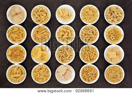 Large pasta dried food selection in round bowls over brown background.