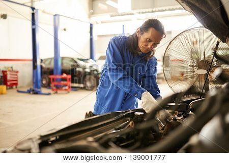 Professional Asian mechanic repairing vehicle in garage