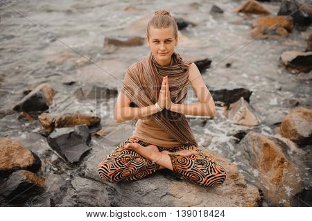 Woman meditating at the beach . yoga retreat. namaste in a lotus pose