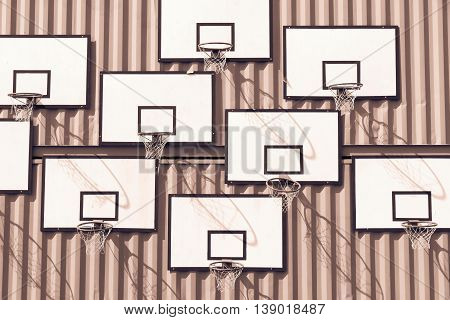 the abstract composition of group of basketball baskets of monochrome tone of brown color with rectangular boards is located on a wall of iron containers