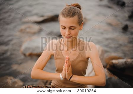 beautiful woman performing namaste with closed eyes gesture on beach