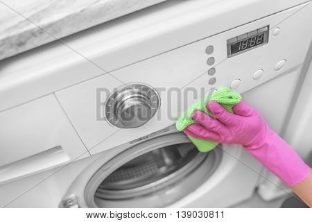 Female hands in gloves washing washing machine. Close-up.