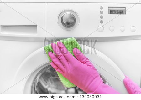 Female hands in gloves washing washing machine. Close-up.