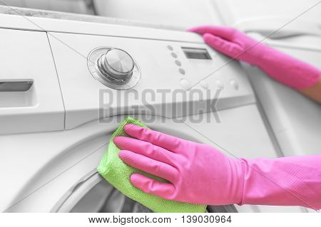 Female hands in gloves washing washing machine. Close-up.