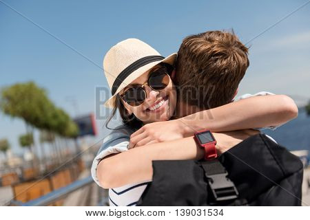 My darling. Pleasant cheerful beautiful woman smiling and embracing with her boyfriend while standing outdoors
