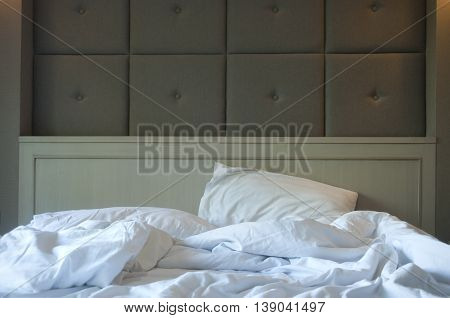 Unmade bed pillow and blanket in a hotel