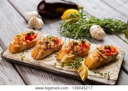 Grilled toasts with fish meat. Lemon slice and small capers. Bruschetta with chopped salmon. Traditional italian appetizer.