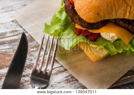 Burger and knife with fork. Ketchup and cream cheese. Special recipe of beefburger. The taste is incredible.