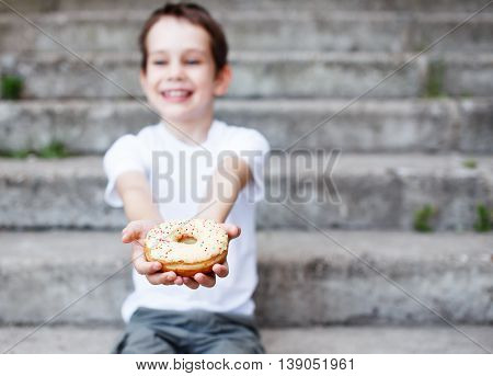 boy giving a donut. smiling child giving a donut to someone. the concept of generosity. selective focus. empty space for your text