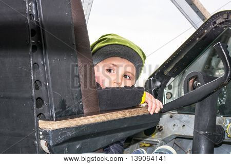 Little boy in the cockpit of an old propeller aircraft