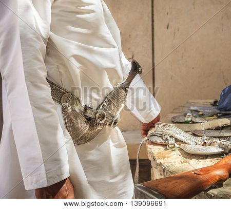 Man wearing khanjar - traditional Omani dagger on a belt at the gun market in Nizwa, Oman