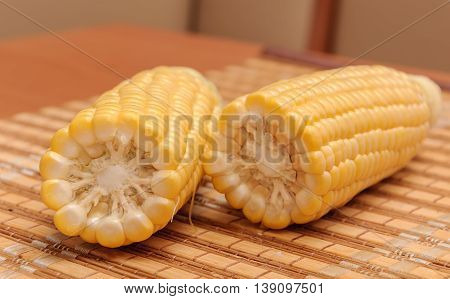 Fresh corn on cobs on rustic wooden table closeup.