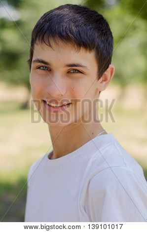 Close up portrait of a young smiling cute teenager with blue eyes. Outdoors.