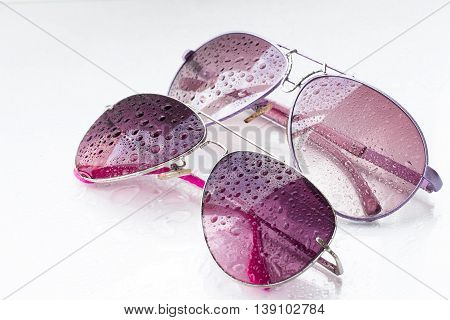 pink sunglasses and drops on an isolated white background