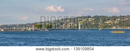 Geneva Switzerland - July 15 2016: Panoramic view of the Bains des Paquis pier and lighthouse. On the right two yellow public transport taxi boats called 
