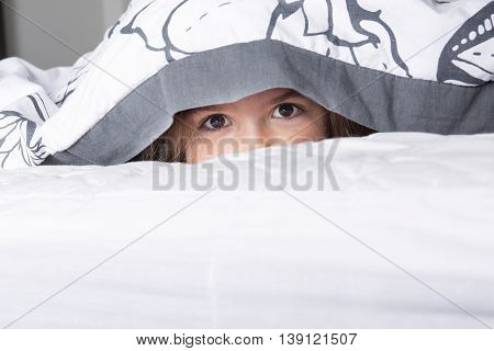 A Child or teen under covers in bed