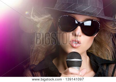 Beautiful woman singing karaoke in spotlight