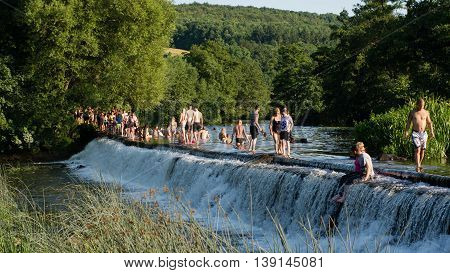 BATH UK - JULY 19 2016
People walking across and swimming in River Avon. Hundreds flock to Warleigh Weir 3 miles from Bath on the hottest day of the year.