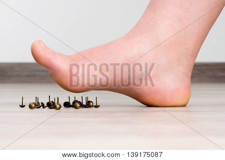 Female foot above pushpin, sharp pin. Feet