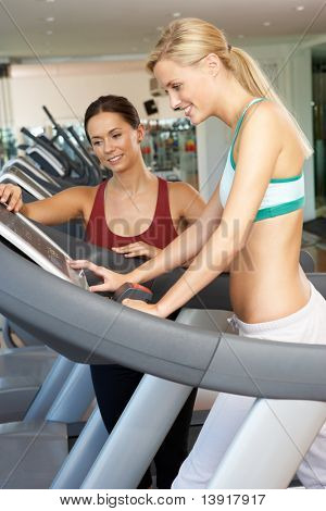 Frau arbeitet mit weiblichen personal Trainer an Maschine im Fitness-Studio ausgeführt