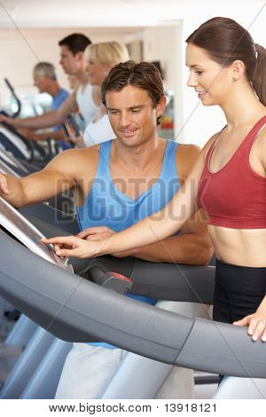 Frau arbeitet mit personal Trainer an Maschine im Fitness-Studio ausgeführt