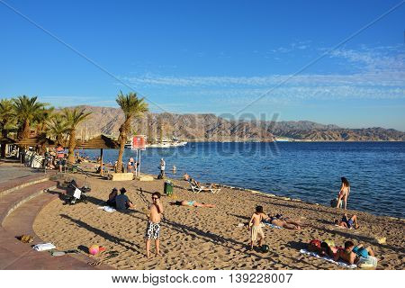 EILAT ISRAEL - MARCH 31 2015: Tourist relaxing on public beach in Eilat at sunset time famous international resort - the southest city of Israel