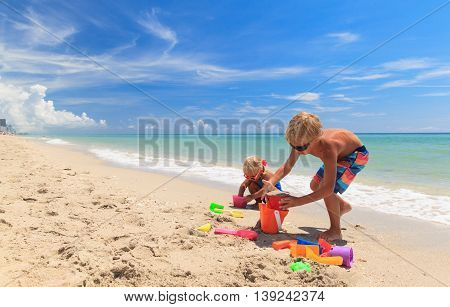 little boy and girl play with sand on summer beach
