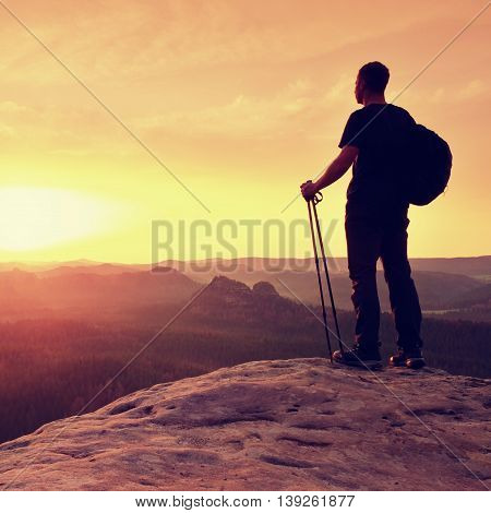 Man With Tourist Poles In Hand And Sporty Backpack Above Valley.