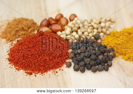 spicies on a wooden plate: chilli pepper coriander curry cinnamon nuts
