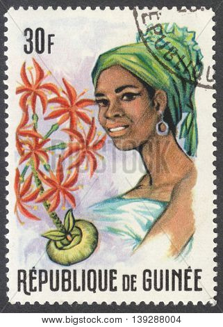 MOSCOW RUSSIA - CIRCA JANUARY 2016: a stamp printed in GUINEA shows a woman in the traditional headdress and a plant Haemanthus sp. the series 
