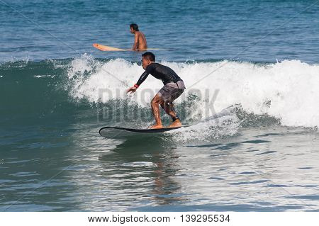 BALI, INDONESIA, 8 April 2016: Surfing in Kuta. Kuta is a beach and resort area in the south of the island of Bali, Indonesia. One of Bali's first tourist developments, it's best known for its Indian Ocean surfing and party-centric atmosphere.