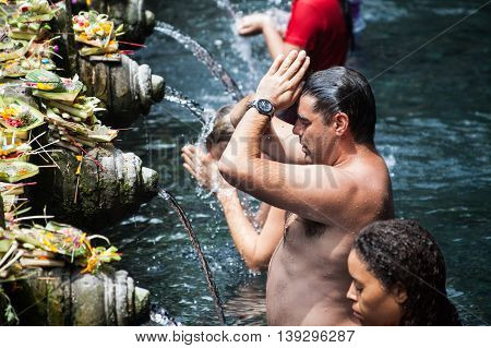 BALI, INDONESIA, 8 April 2016: Praying in Tirta Empul. Tirta Empul temple is a Hindu Balinese water temple located near the town of Tampaksiring, Bali, Indonesia. The temple compound consists of a petirtaan or bathing structure, famous for its holy spring