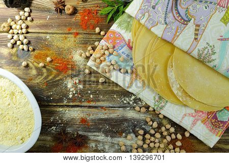 Colorful Indian food - papadum chickpea gram flour and spices on textured wooden table top