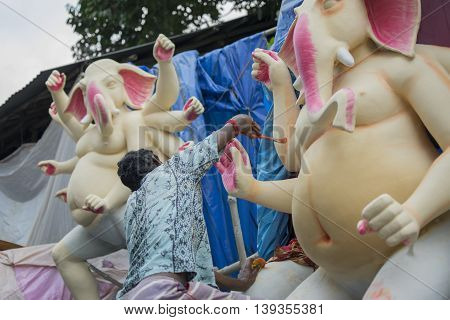 KOLKATA WEST BENGAL INDIA - 13 SEPTEMBER 2015: An unidentified artist paints a clay idol of Lord Ganesha as preparation for 